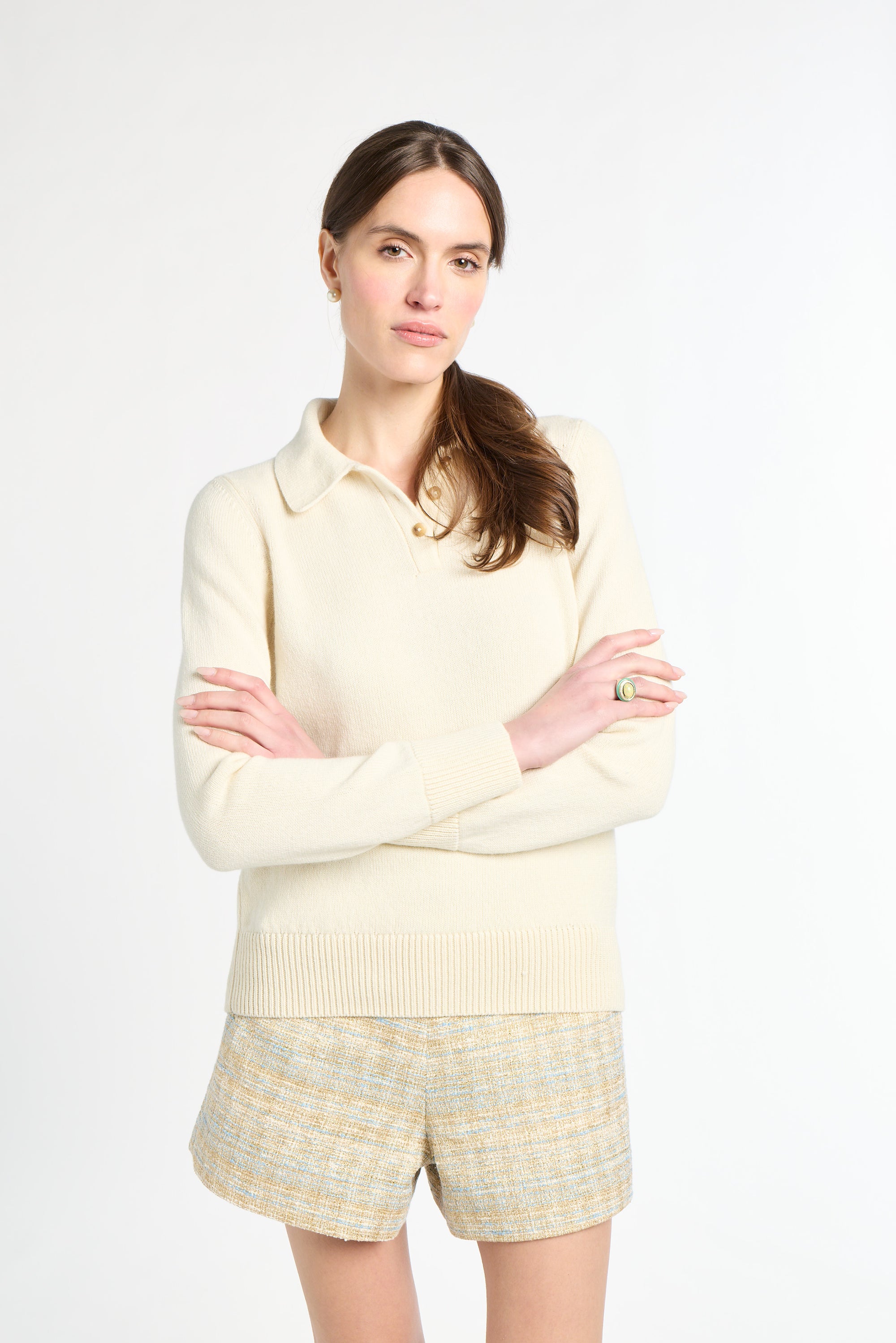 Woman wearing a cream-colored sweater and shorts on a white background