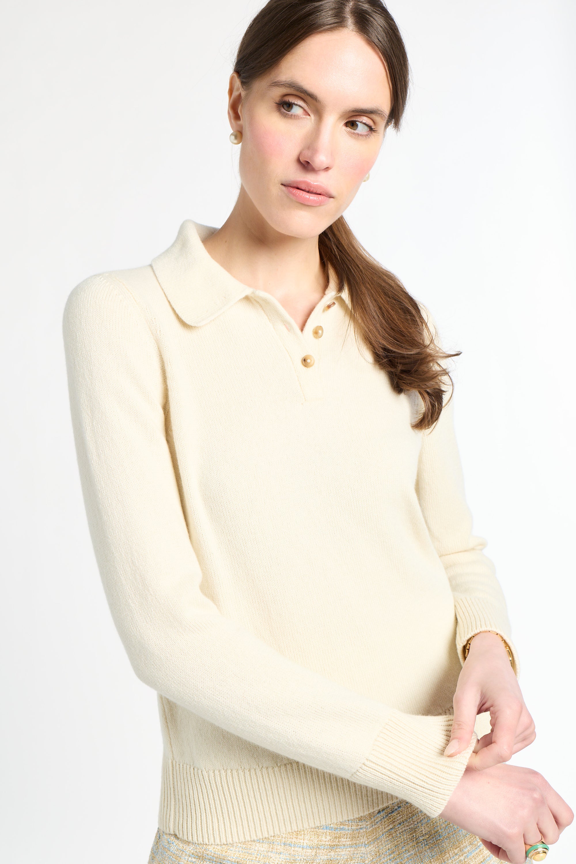 Woman wearing a cream-colored sweater against a white background