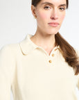 Woman wearing a light-colored polo shirt against a white background