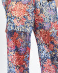 Floral patterned pants with a mix of red, blue, and pink colors on a white background.
