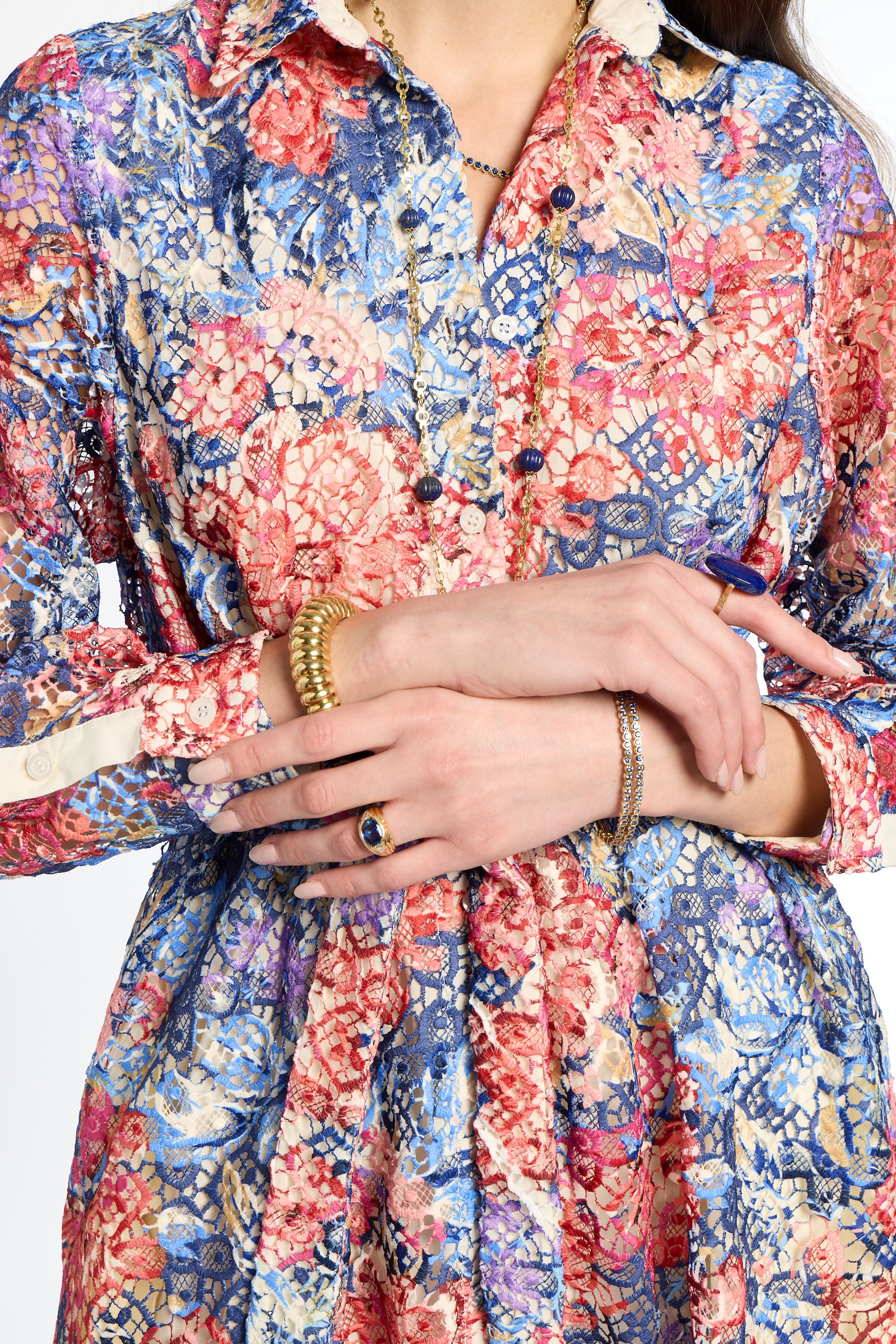 Close-up of a person wearing a colorful floral dress with hands clasped together.