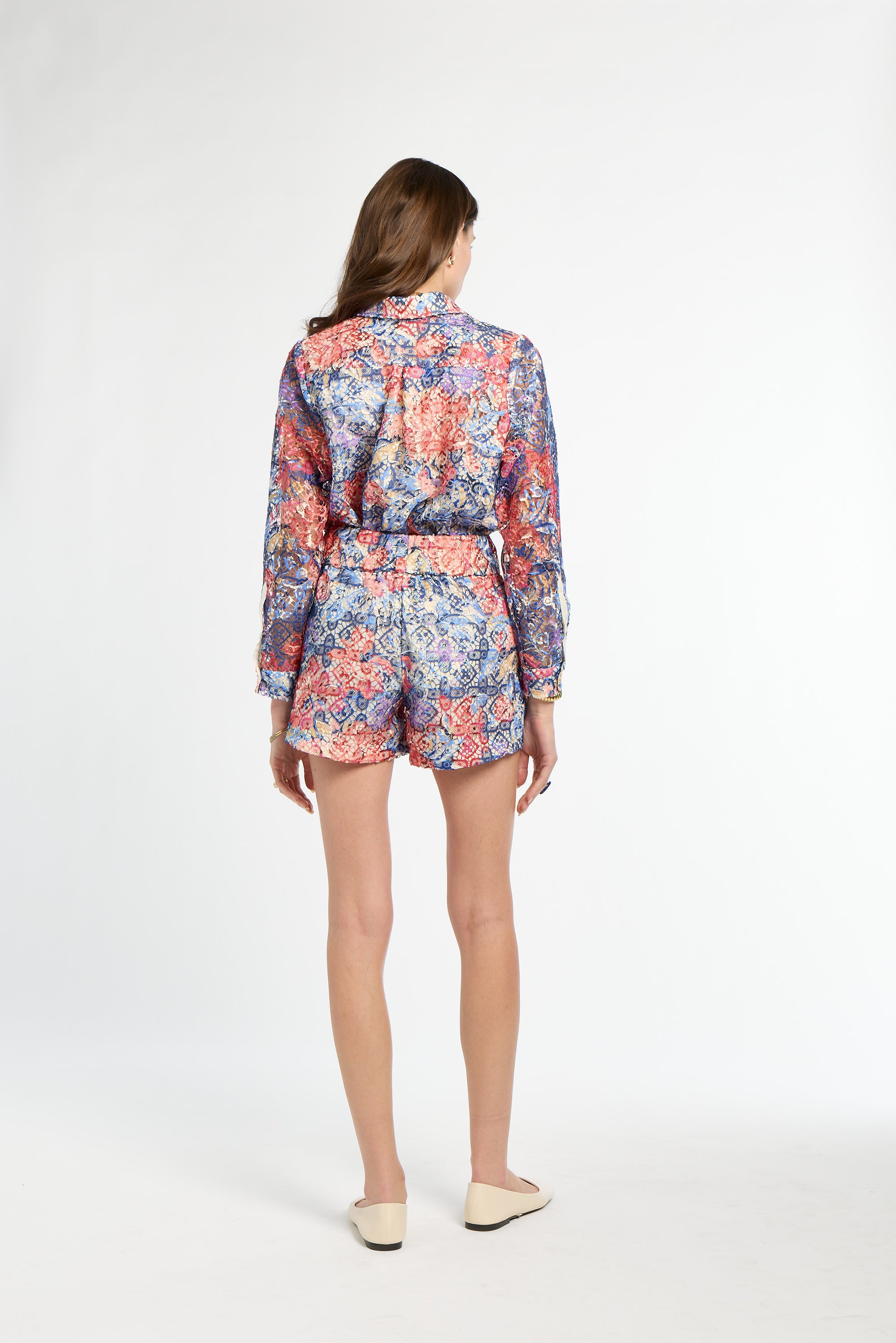 Woman wearing a colorful floral romper on a white background