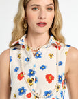 Woman wearing a sleeveless blouse with colorful floral pattern and pearl necklace on a white background