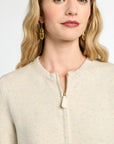 Woman wearing a beige zip-up jacket with a plain background