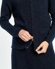 Navy blue coat with a close-up of a hand zipping it up on a white background