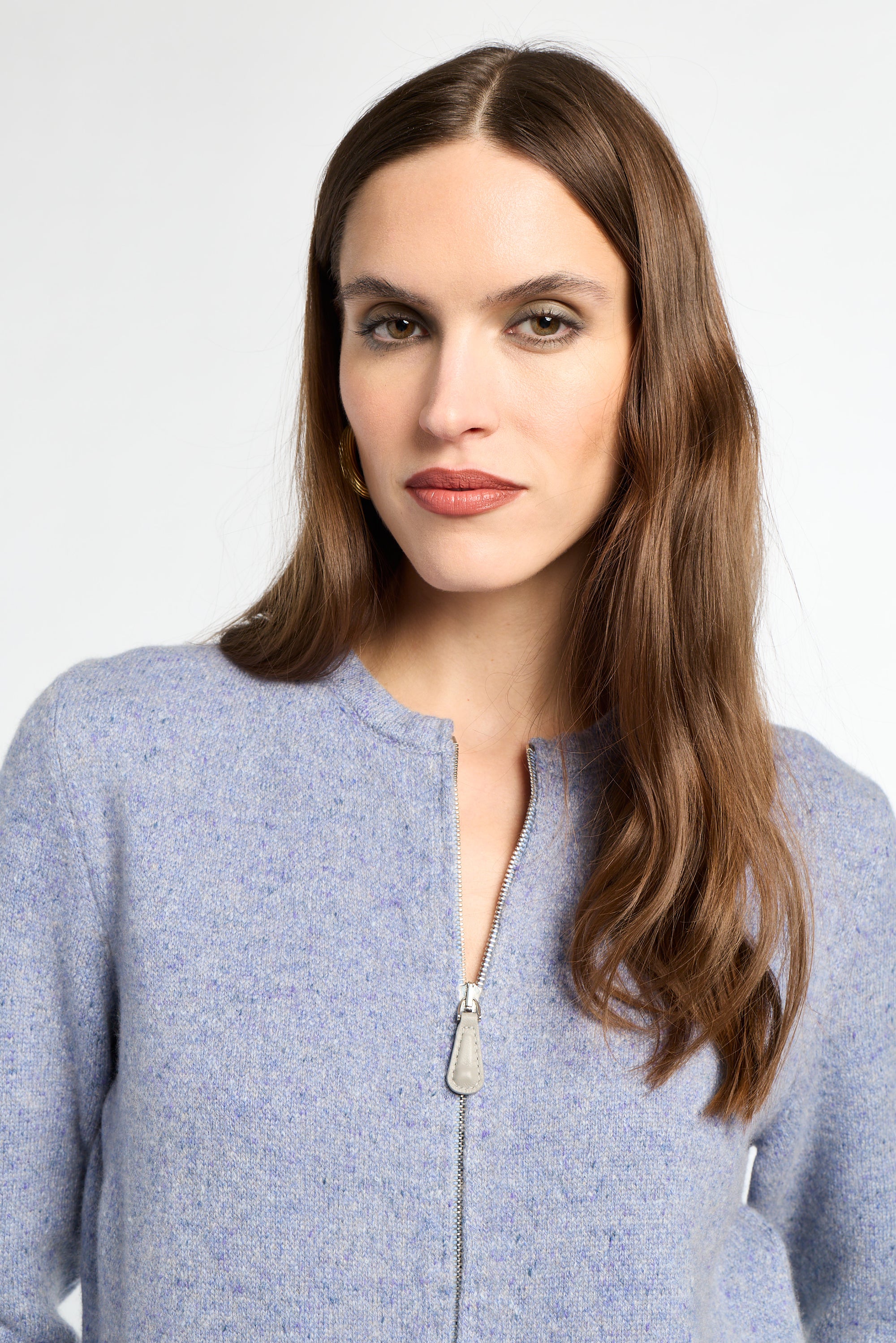 Woman wearing a light blue zip-up sweater against a white background