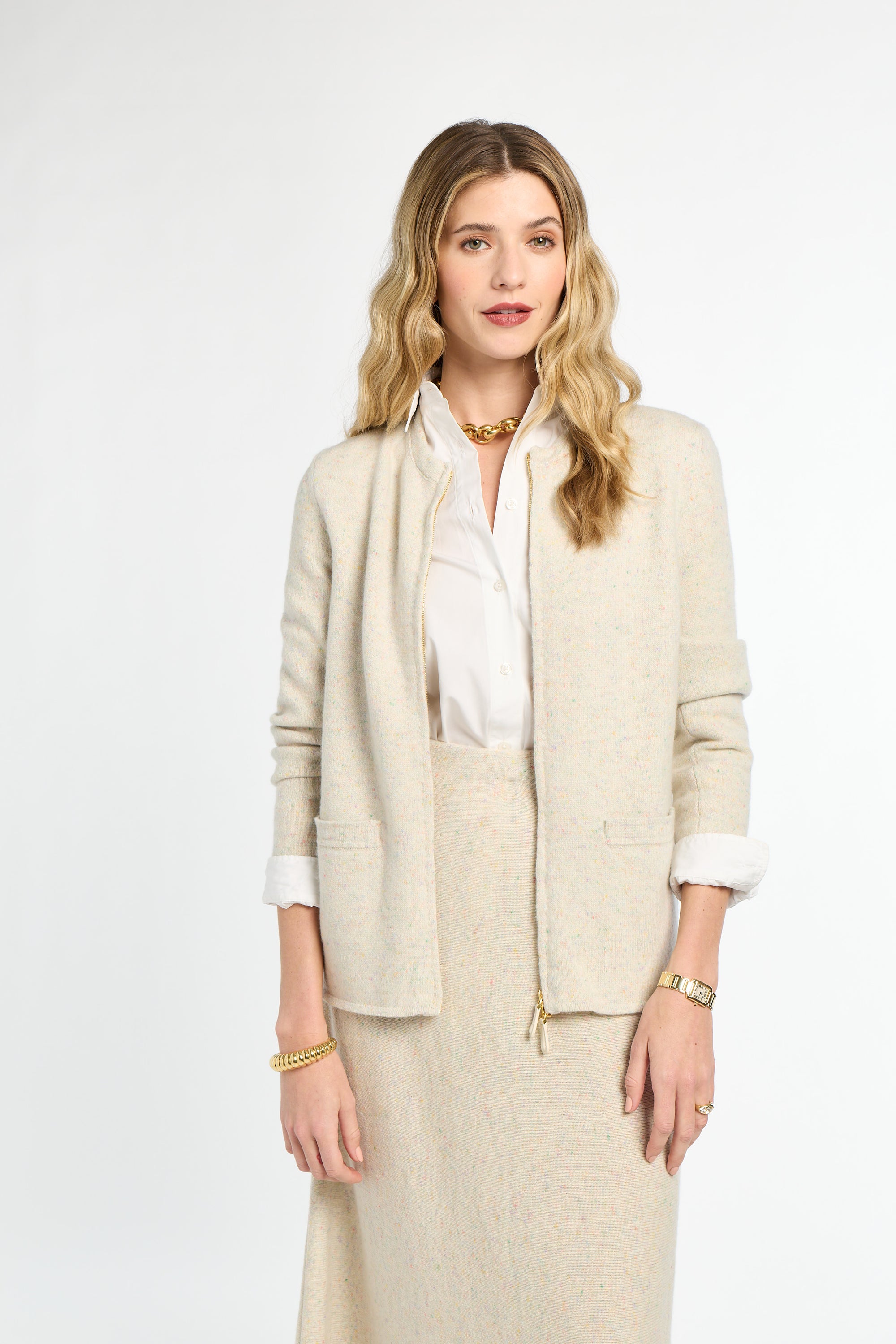 Woman wearing a beige suit with a white shirt on a light gray background