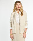 Woman wearing a beige suit with a white shirt on a light gray background