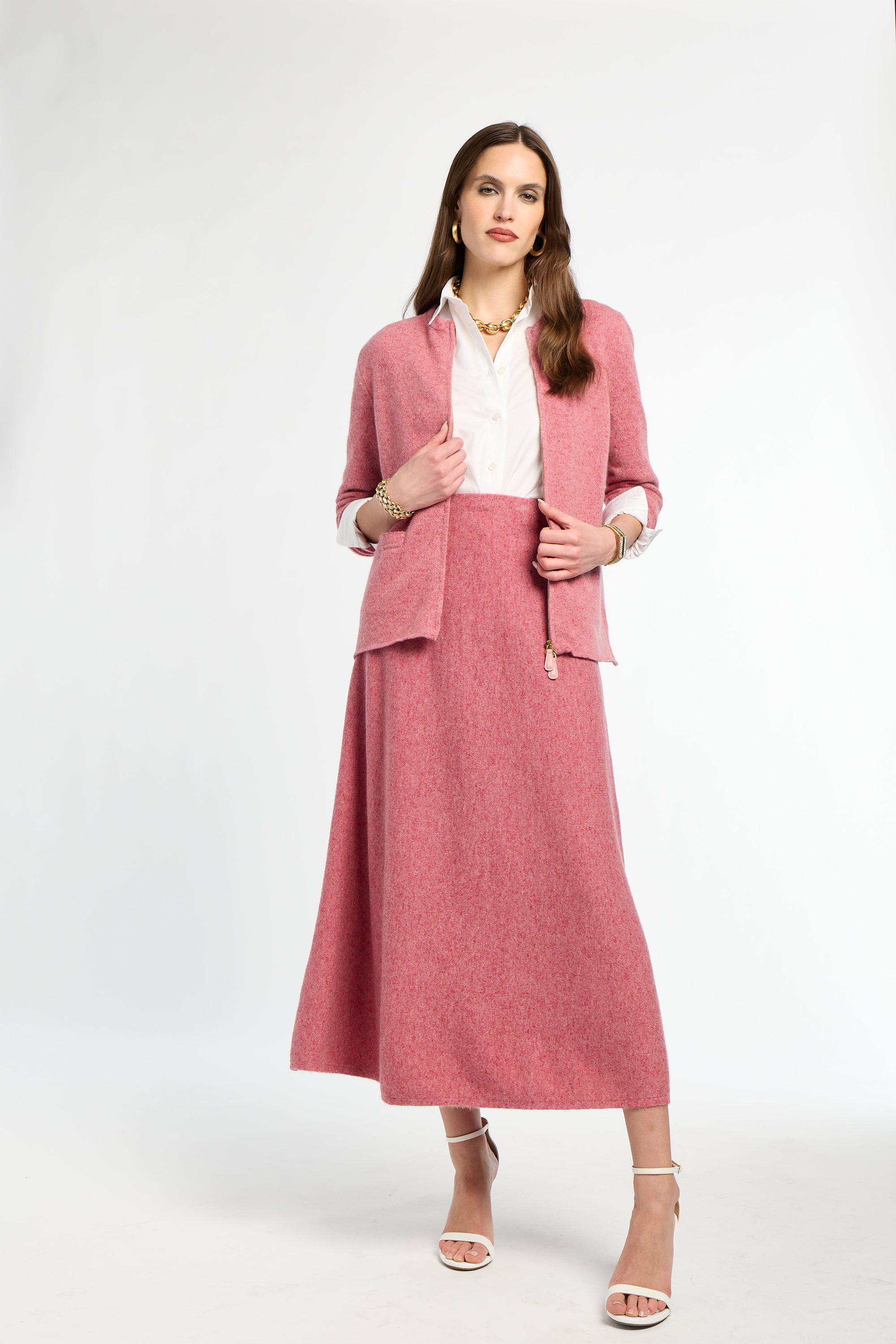 Woman wearing a pink suit with a white top on a white background