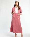 Woman wearing a pink suit with a white top on a white background