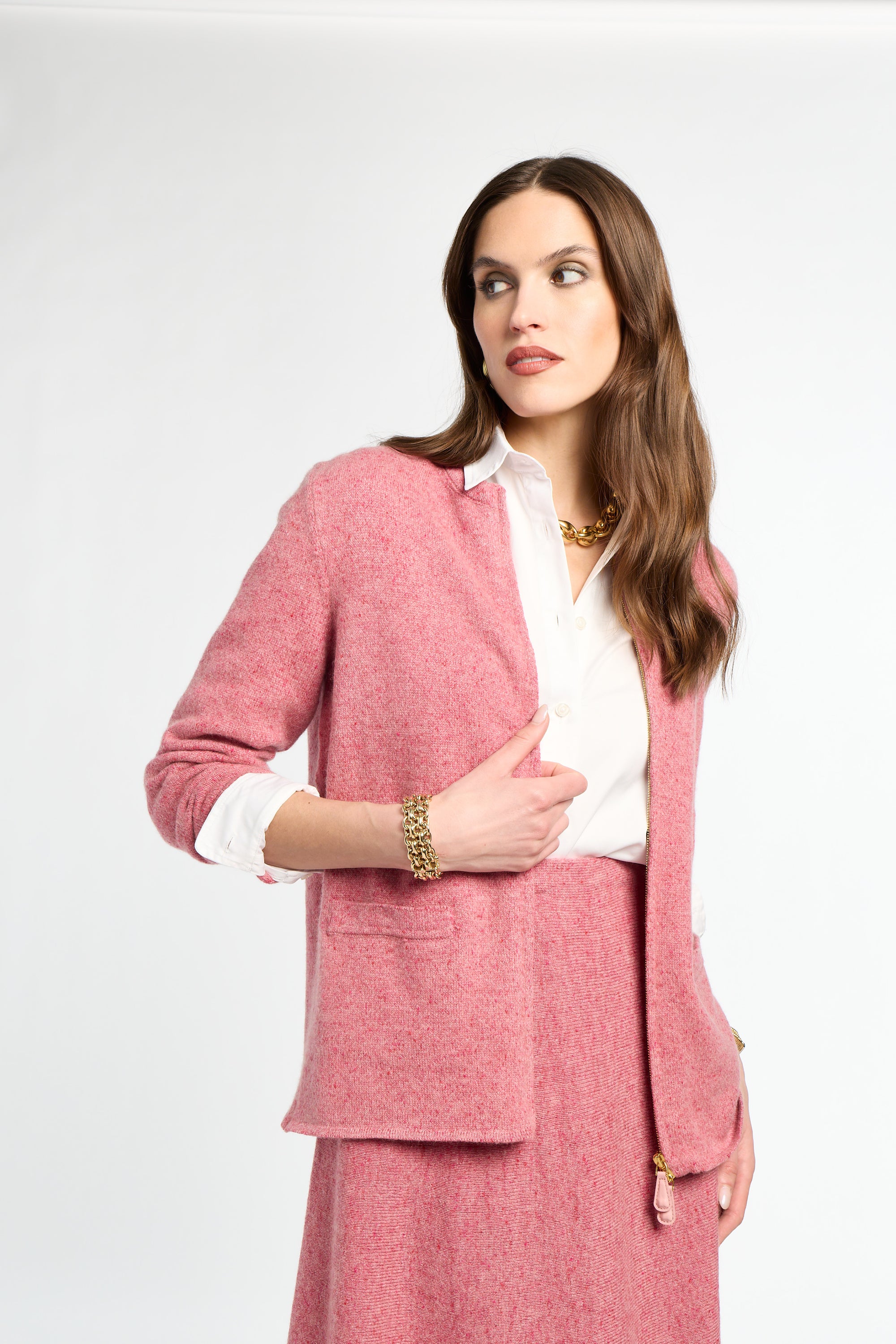 Woman wearing a pink suit with a white shirt on a light gray background