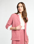 Woman wearing a pink suit with a white shirt on a light gray background