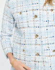 Close-up of a textured blue and white dress with gold buttons.