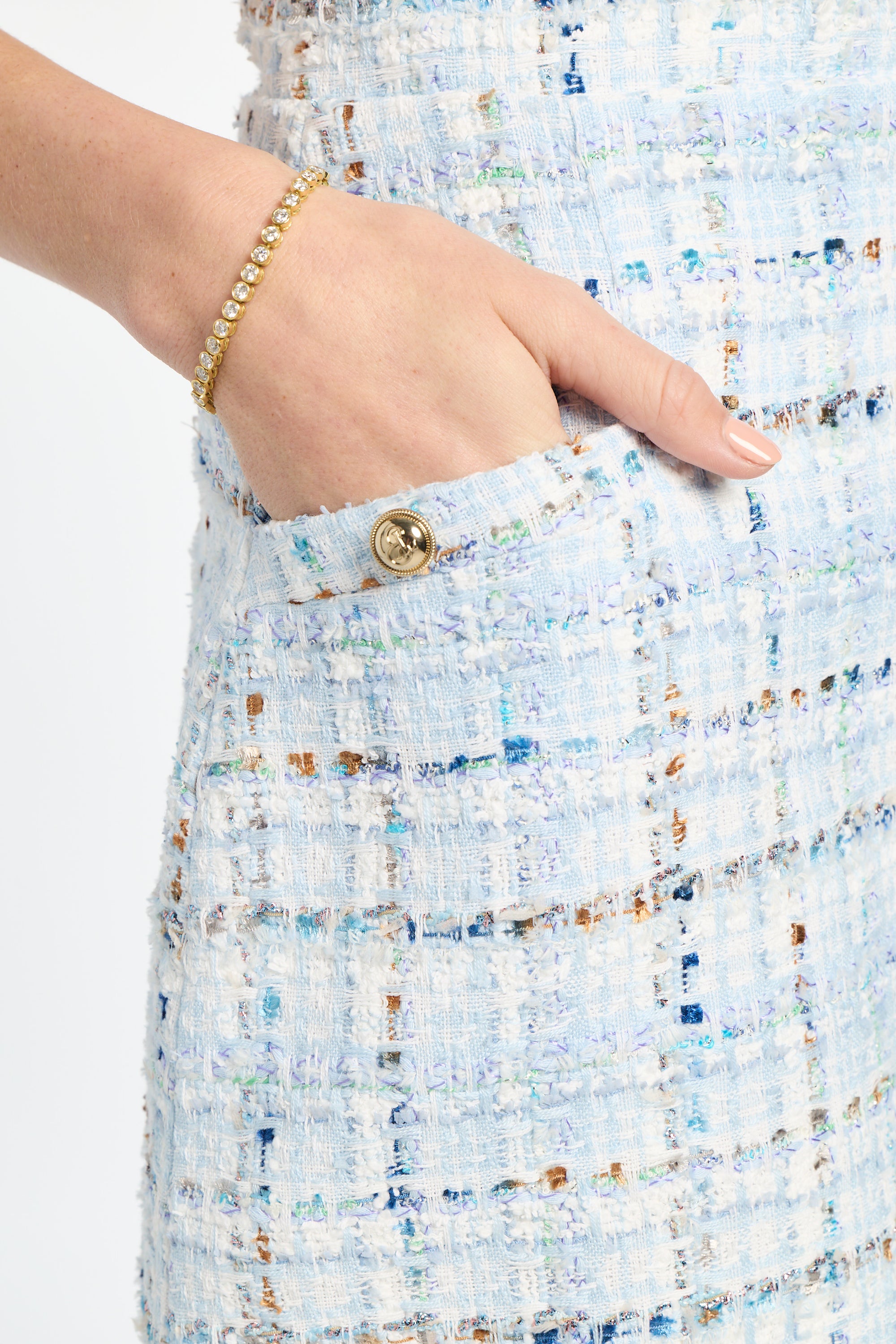Close-up of a hand wearing a gold bracelet on a textured fabric background