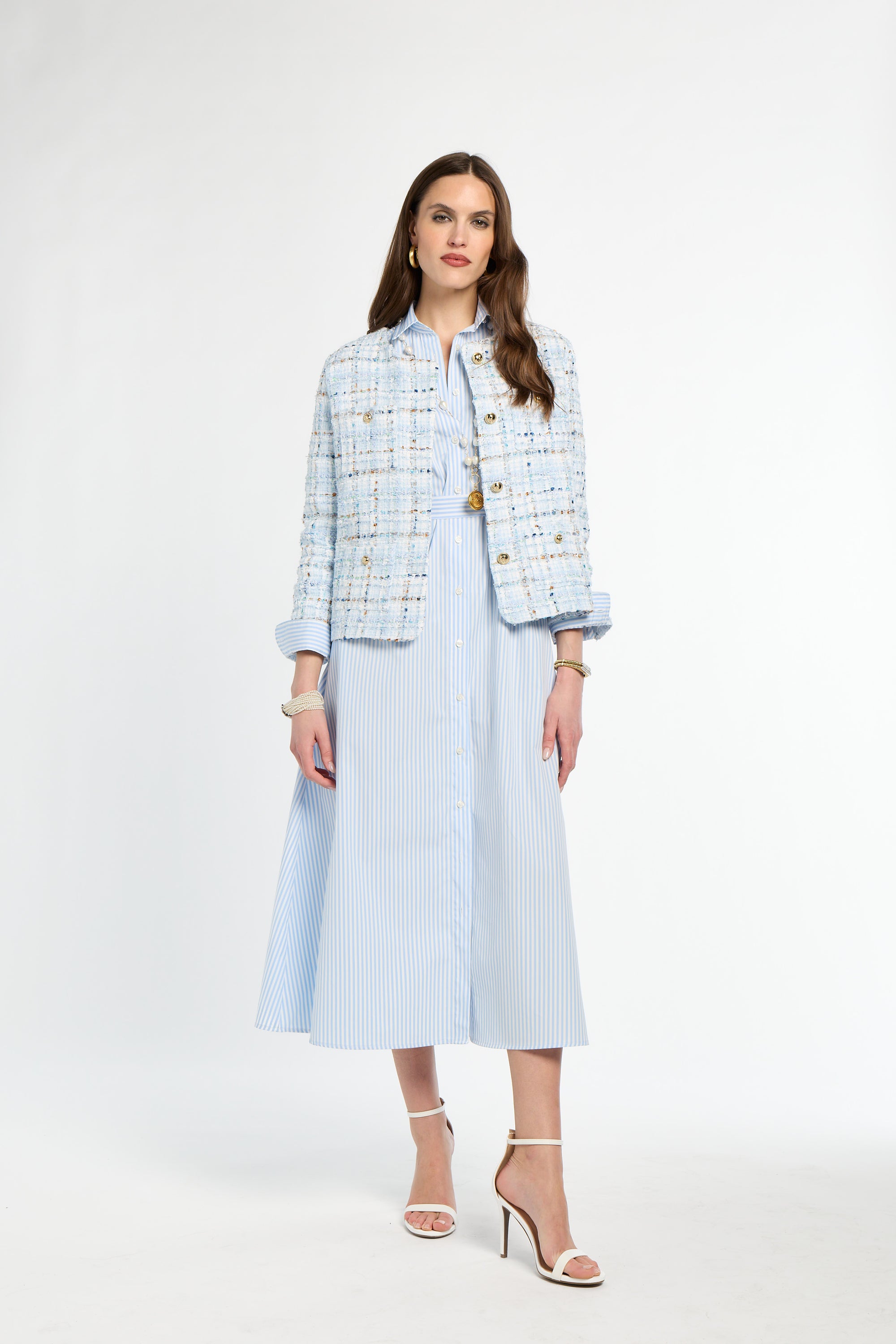 Woman wearing a light blue tweed jacket and matching skirt on a white background