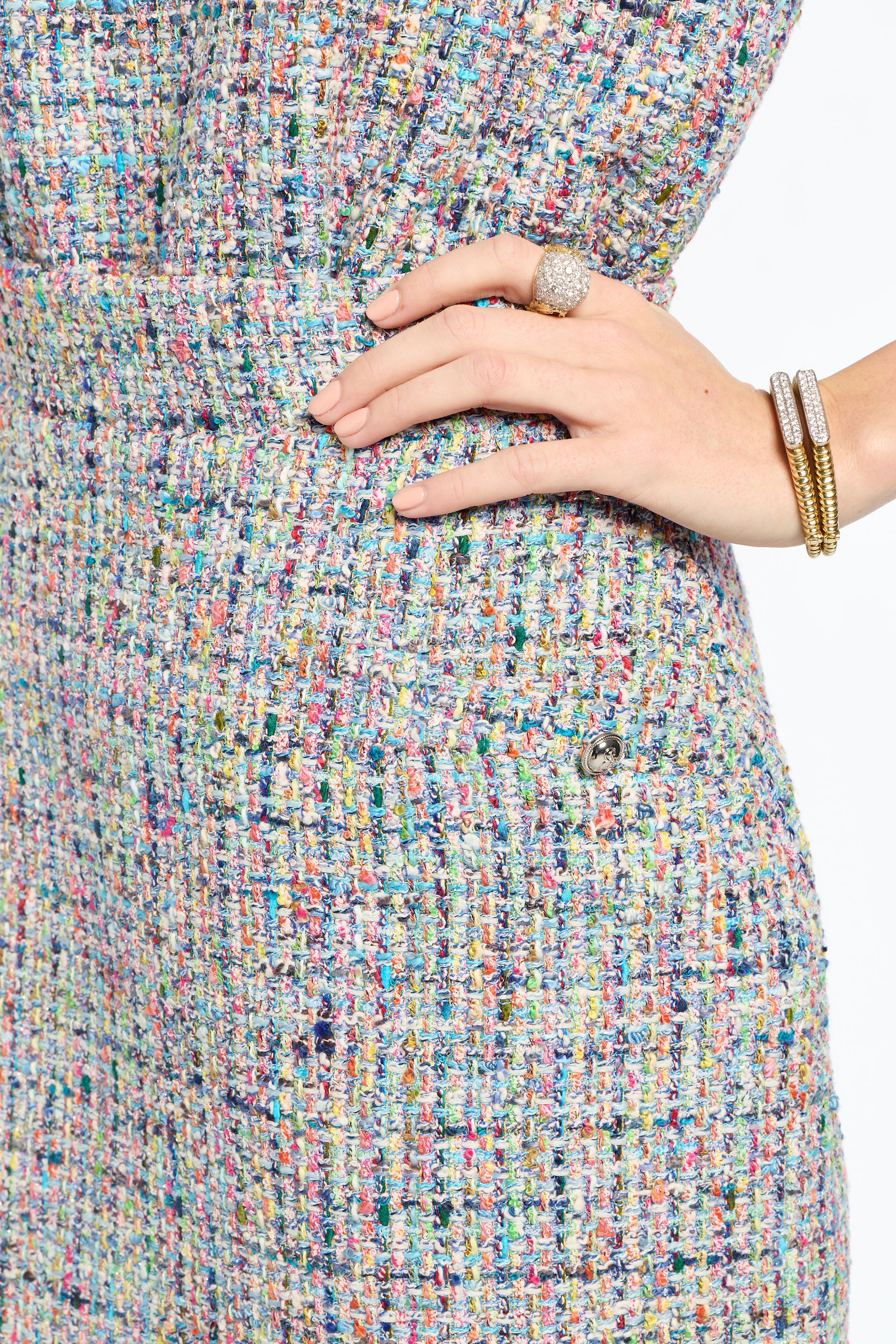 Multicolored textured fabric with a hand wearing a ring and bracelet on a white background