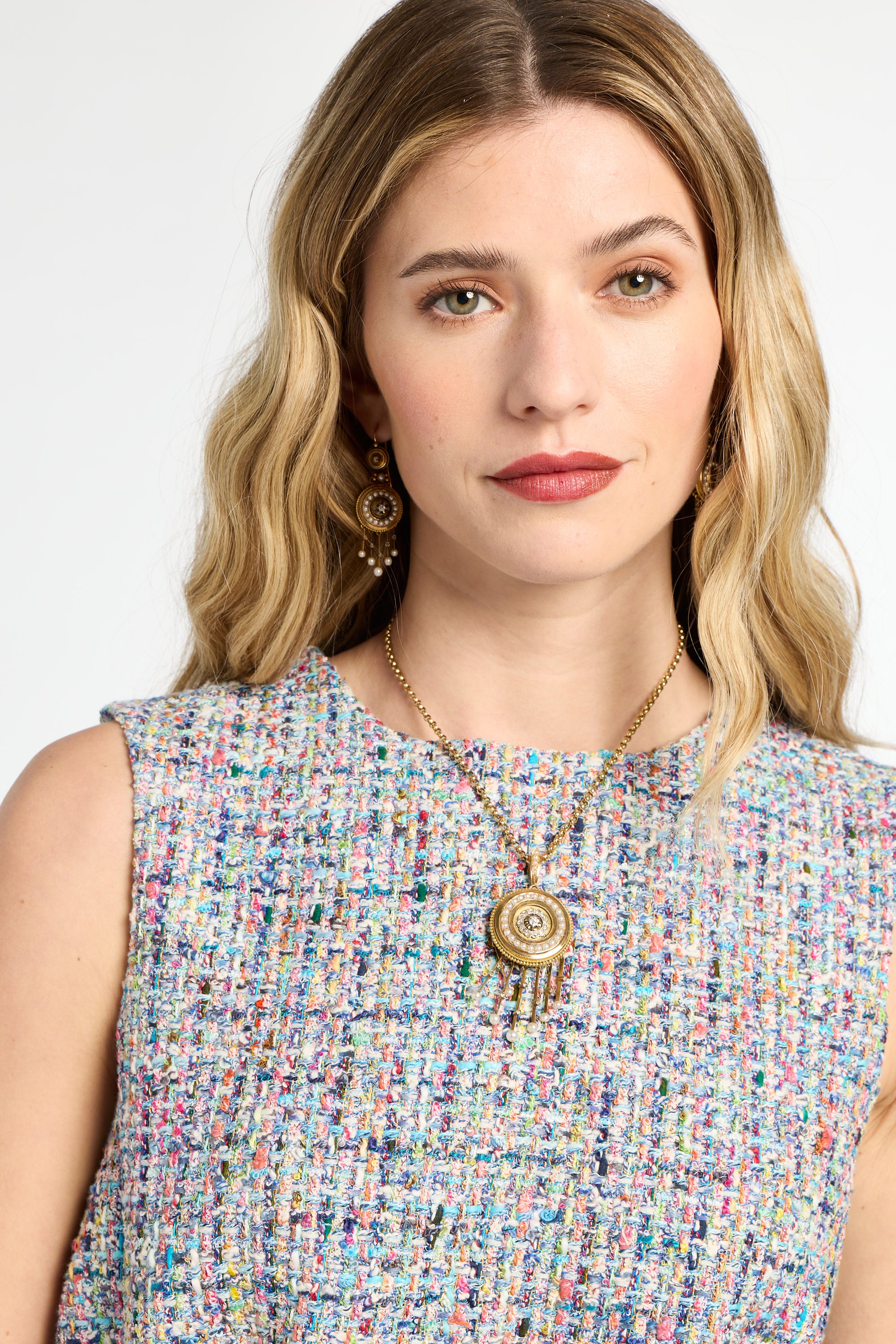 Woman wearing a colorful patterned dress with a necklace and earrings on a white background