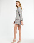 Woman wearing a checkered blazer and shorts on a white background