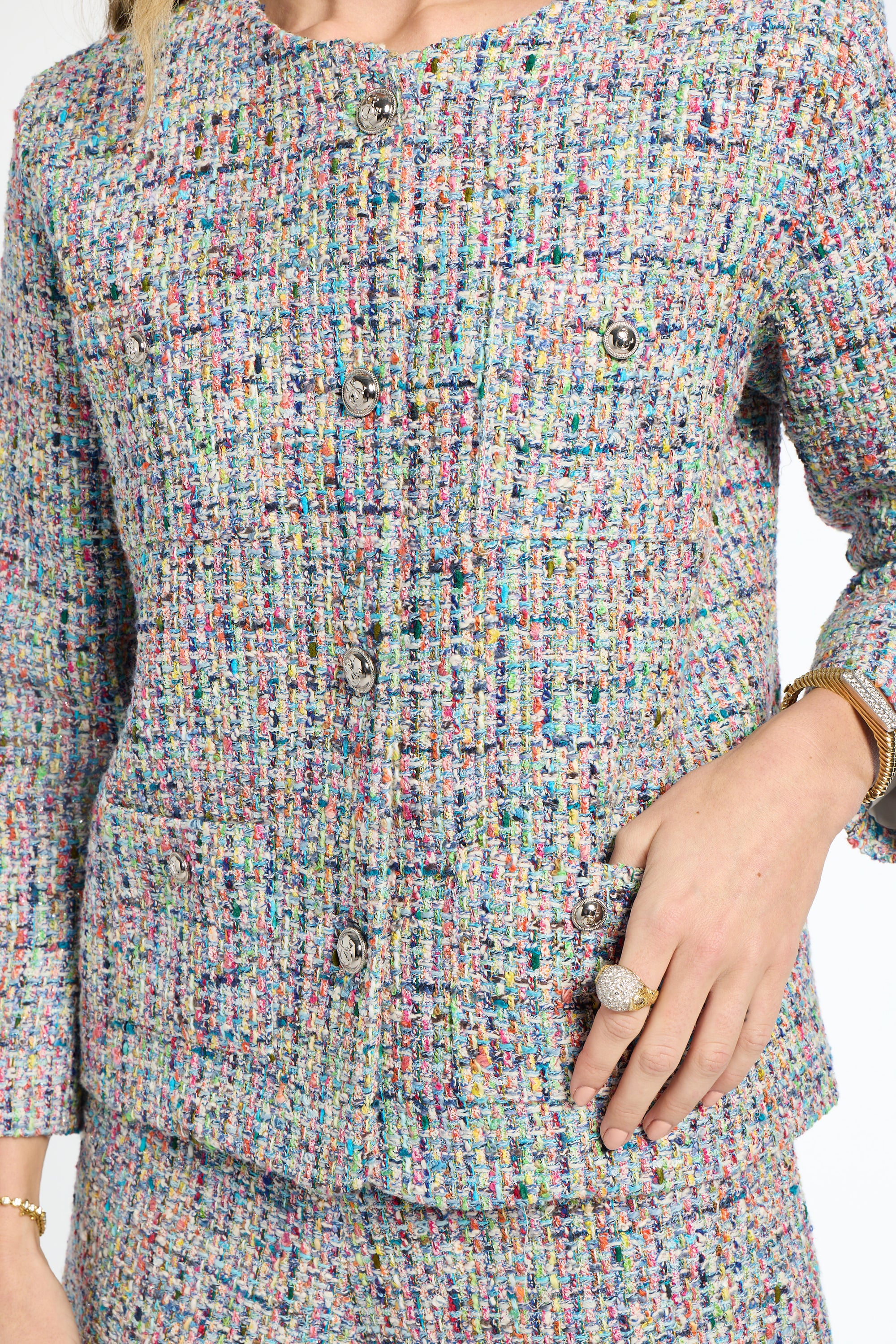 Multicolored textured outfit with a close-up of the fabric and a hand wearing a ring.