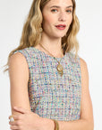 Woman wearing a multicolored sleeveless top with jewelry on a white background