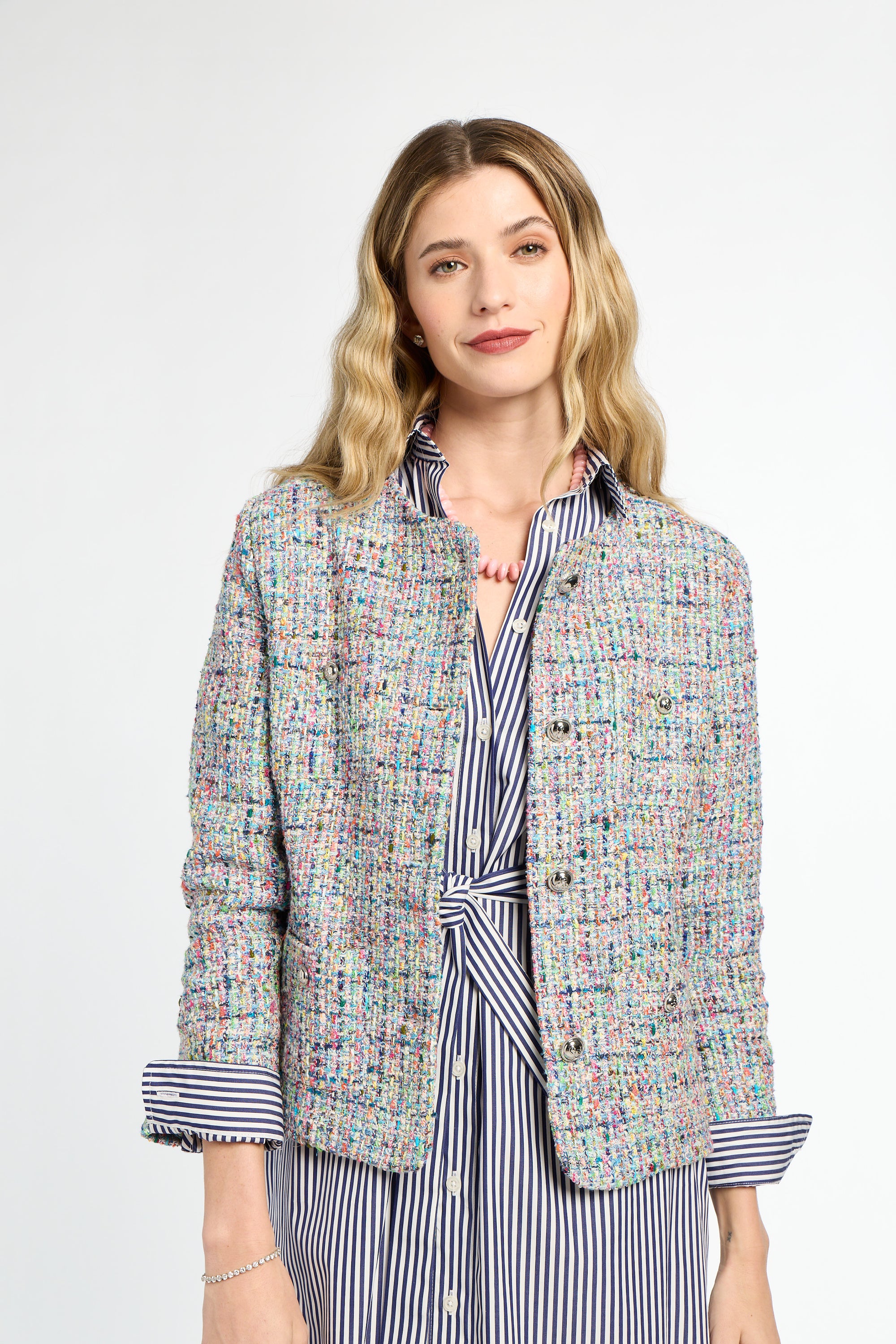 Woman wearing a multicolored tweed jacket over a striped shirt on a white background