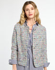 Woman wearing a multicolored tweed jacket over a striped shirt on a white background
