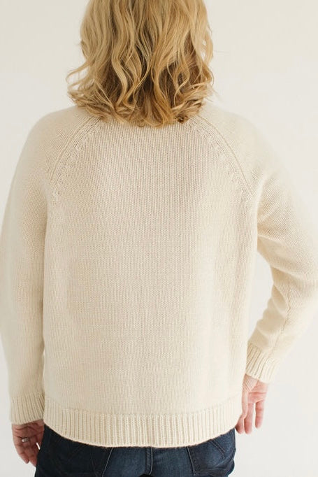 Back view of Eleanor Leftwich wearing the Boyfriend Turtleneck sweater in Cream, paired with dark jeans, against a white background.