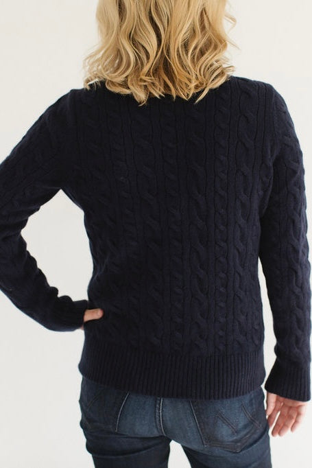 Back view of Eleanor Leftwich in the Navy Cable-Knit Turtleneck sweater paired with dark denim against a white background.