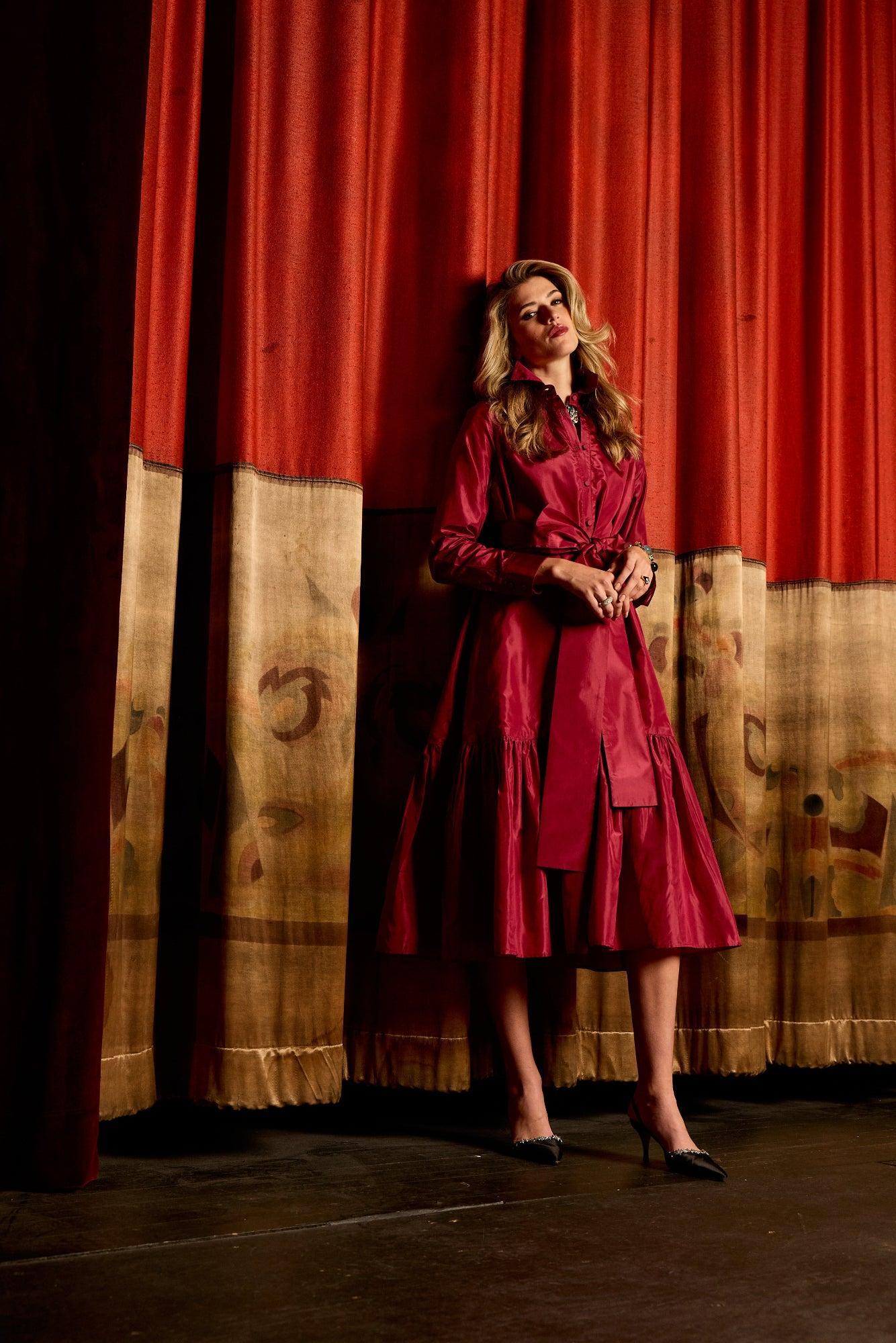 Woman in a red dress standing on a stage with red curtains