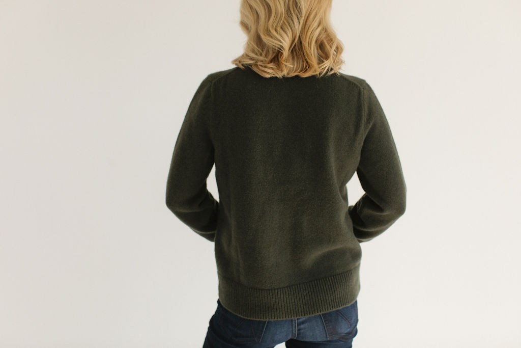 Back view of Eleanor Leftwich wearing the Green Classic Cashmere Crew, paired with dark jeans and standing against a white background.