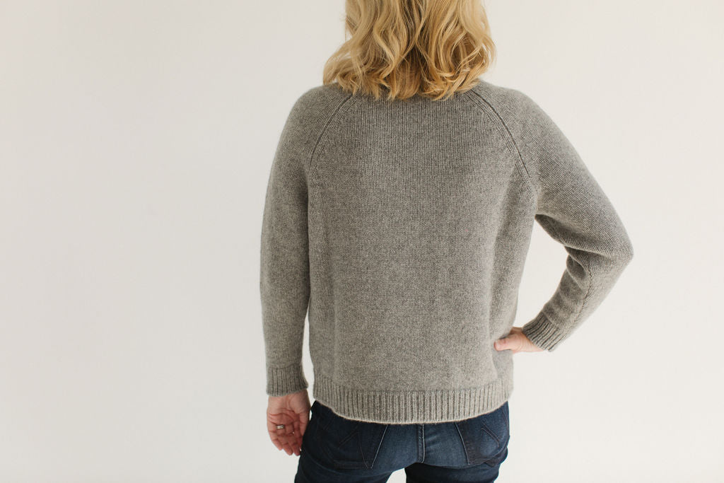 Back view of Eleanor Leftwich wearing the Boyfriend Turtleneck sweater in Gray, paired with dark jeans, against a white background.