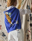 Person wearing a blue sweater with a colorful design, standing in front of a textured wall.