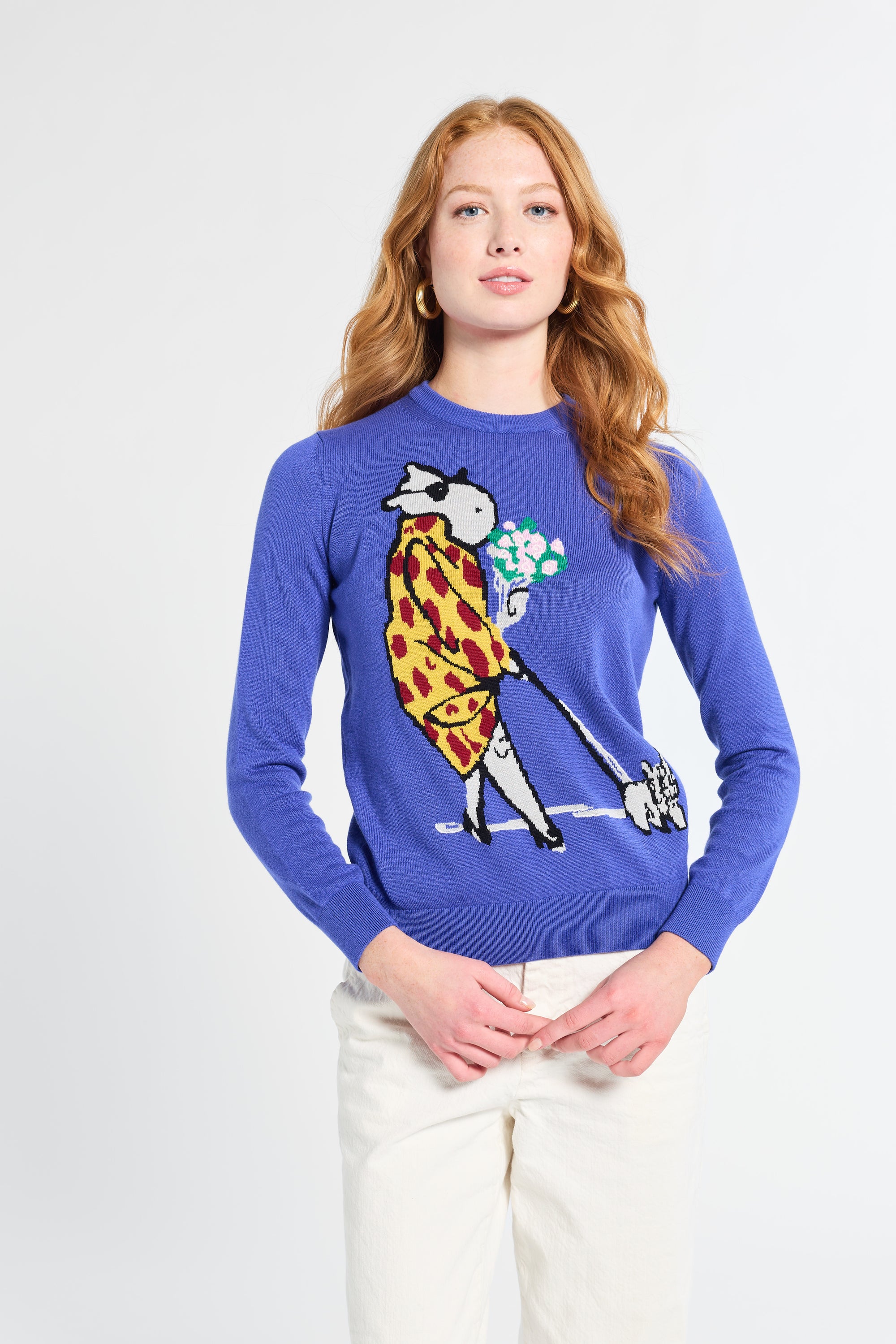 Person wearing a blue sweater with a painted character design on a plain background