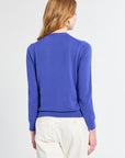 Person wearing a blue sweater and white pants on a plain background