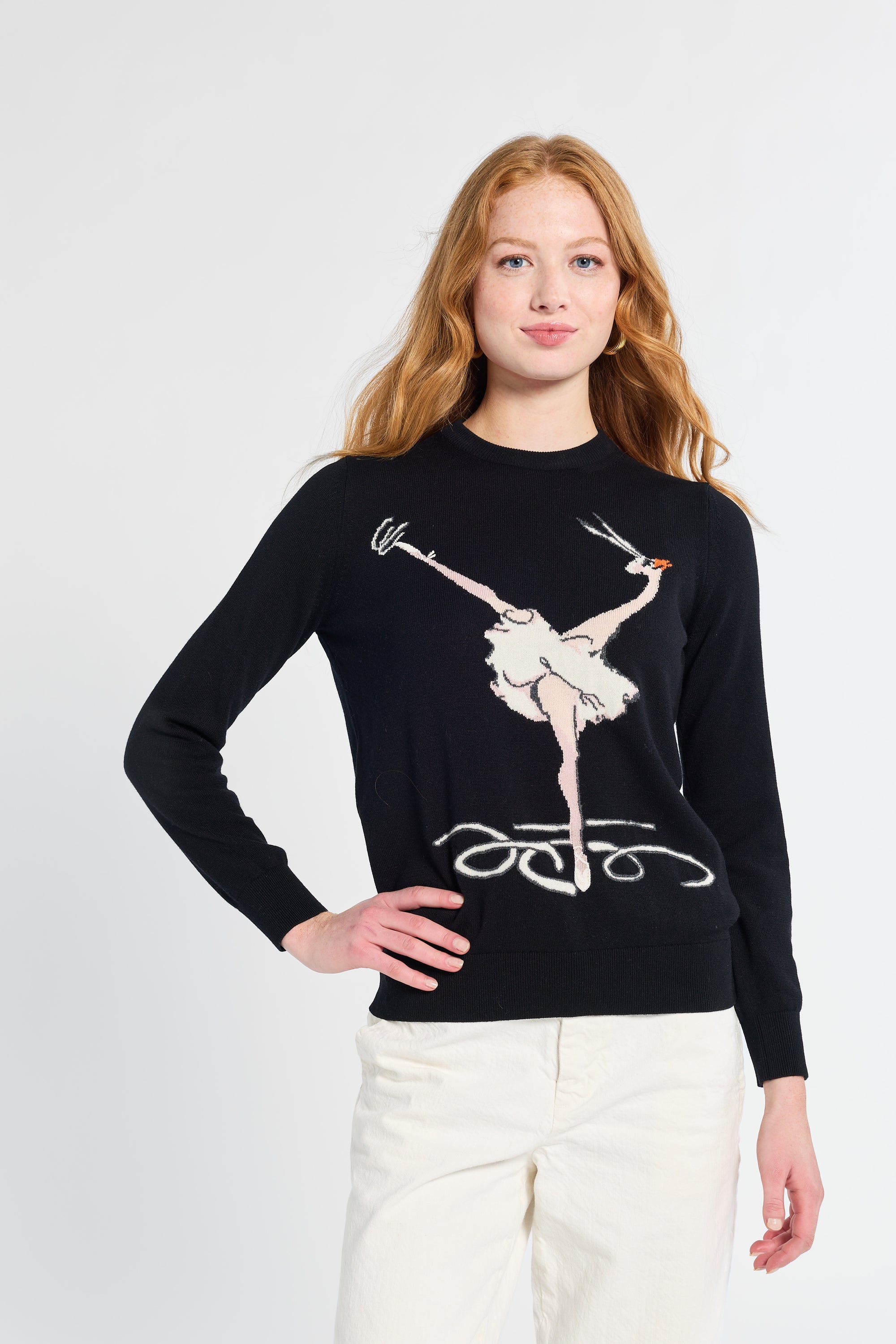 Woman wearing a black sweater with a graphic design of a ballerina on a white background