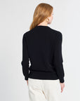 Person wearing a black sweater and white pants on a light gray background