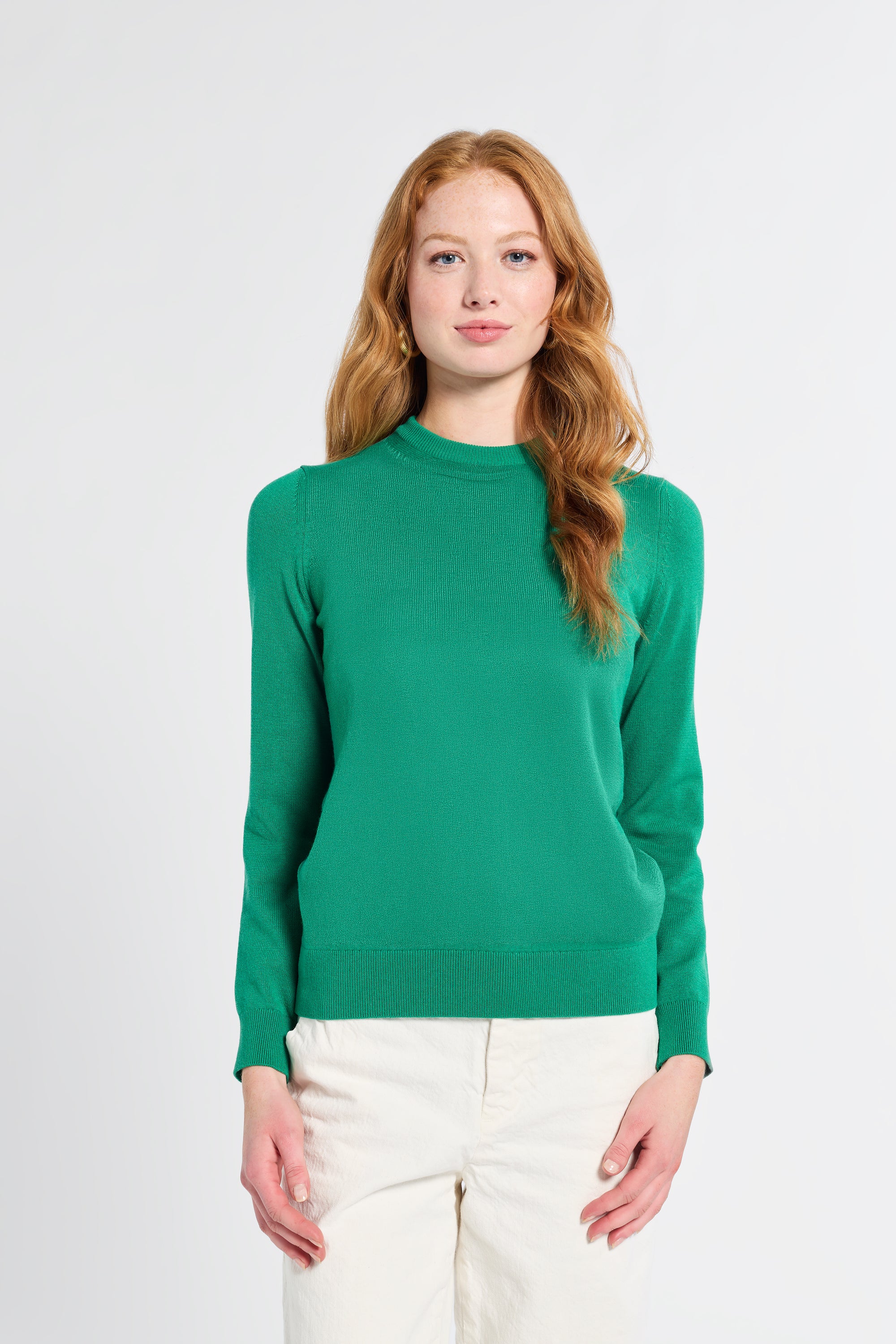 Woman wearing a kelly green cashmere sweater on a white background