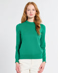 Woman wearing a kelly green cashmere sweater on a white background