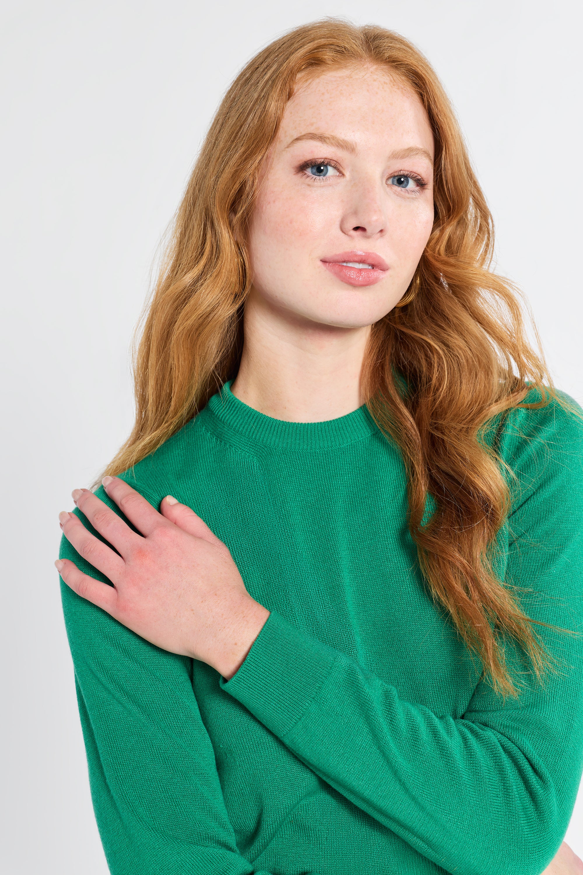 Woman wearing a cashmere silk knit green sweater against a white background