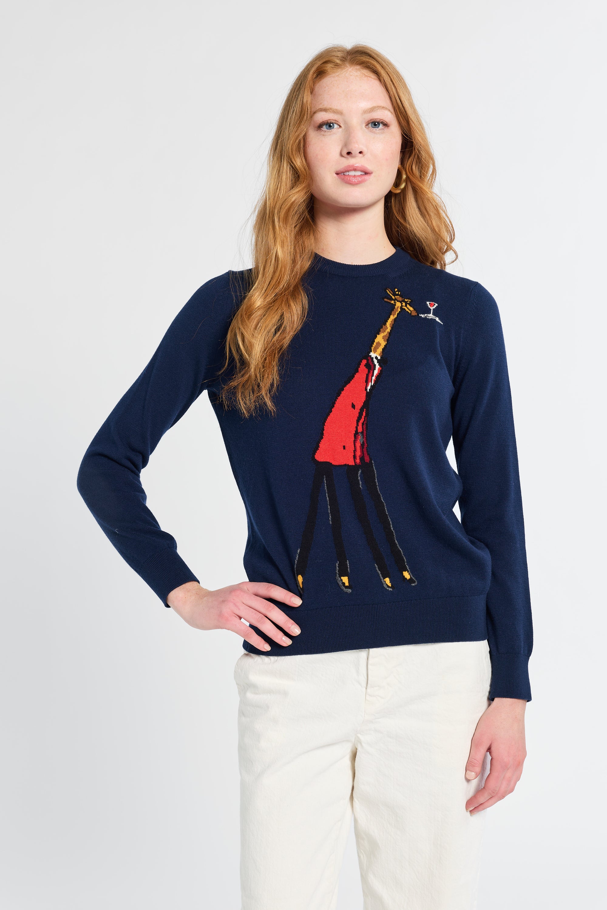 Woman wearing a navy sweater with a colorful giraffe design on a white background