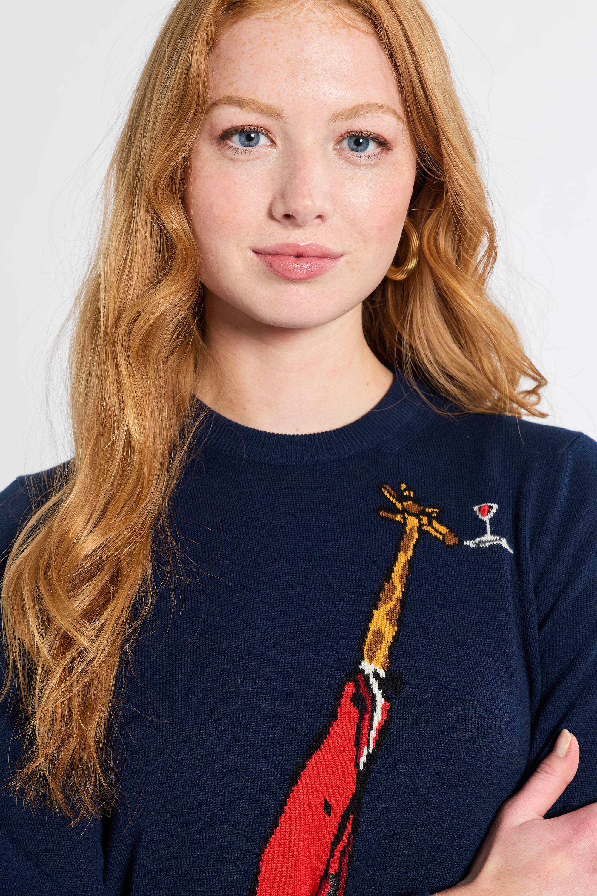 Woman wearing a navy blue sweater with a red and yellow giraffe design on a white background