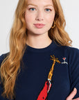 Woman wearing a navy blue sweater with a red and yellow giraffe design on a white background
