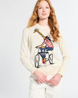 Woman wearing a cream sweater with a design of a giraffe on a bike on a white backdrop