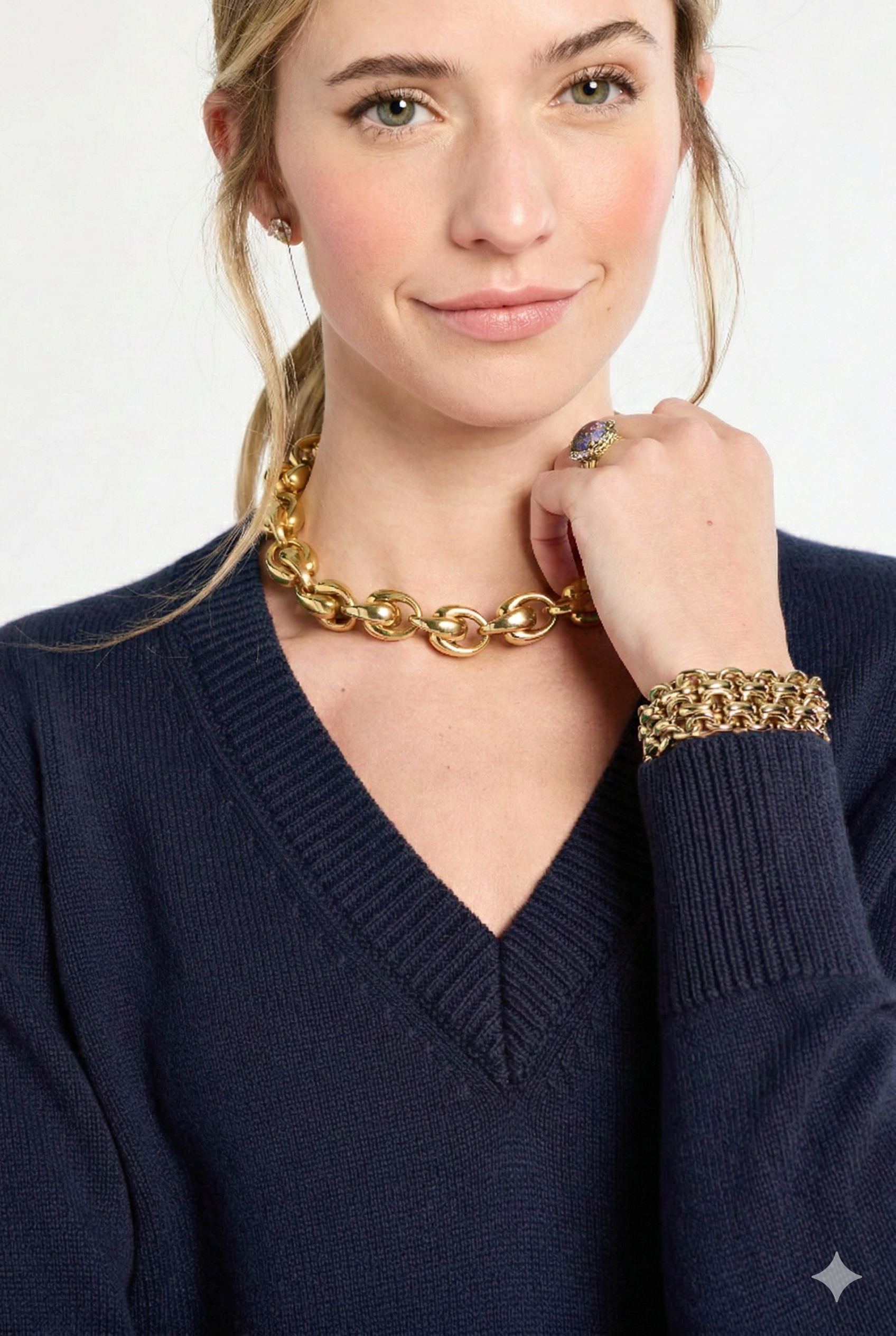 close up of woman wearing navy v-neck sweater with gold jewelry