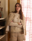 Woman wearing tweed shorts and blazer while standing in front of a window