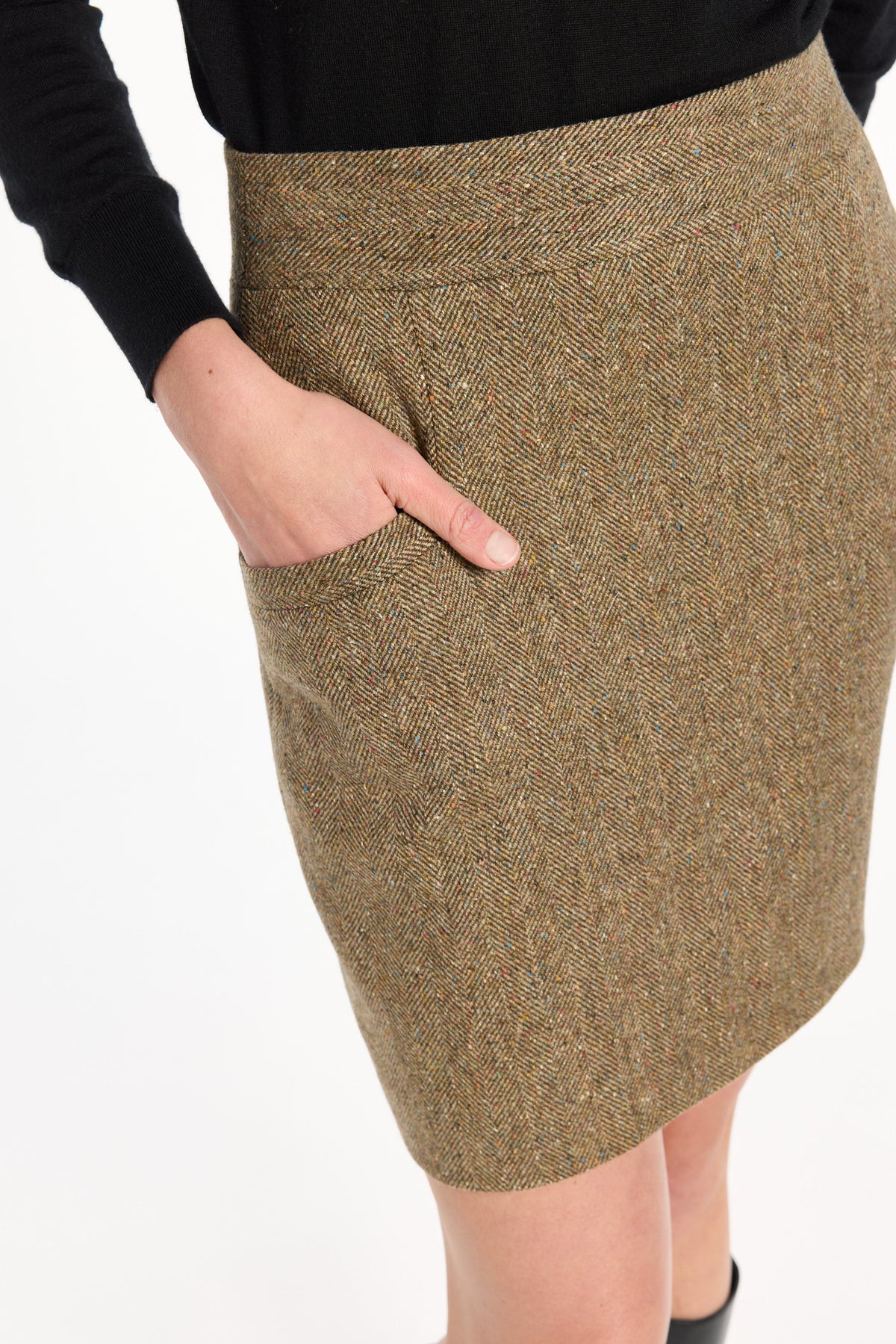 Close-up of the pocket and flecked herringbone texture of the Meg Mini Skirt, photographed against a plain white studio background.