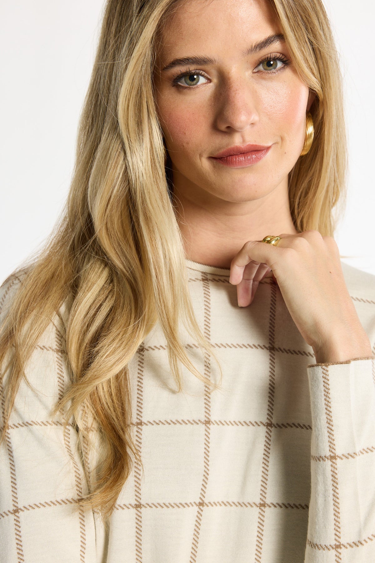 Close-up of the cream windowpane plaid neckline and knit texture of the Reversible Crewneck, photographed against a plain white studio background.
