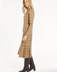 A woman modeling the chestnut side of the Windowpane Plaid Reversible Crewneck with the matching skirt, side view, photographed against a plain white studio background.