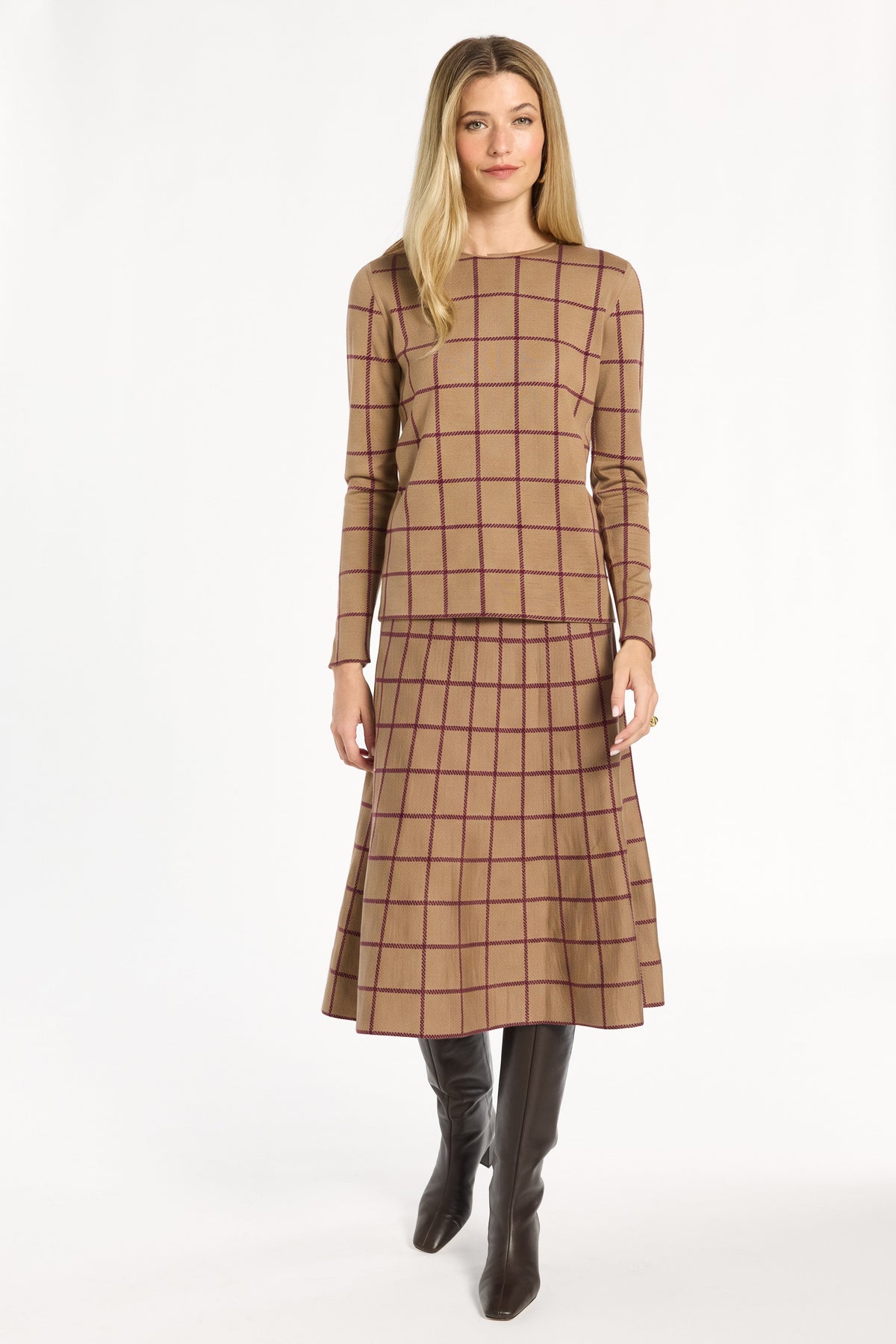 A woman modeling the chestnut reverse of the Cranberry Windowpane Plaid Crewneck with the matching skirt and black boots, front view, photographed against a plain white studio background.