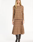 A woman modeling the chestnut reverse of the Cranberry Windowpane Plaid Crewneck with the matching skirt and black boots, front view, photographed against a plain white studio background.